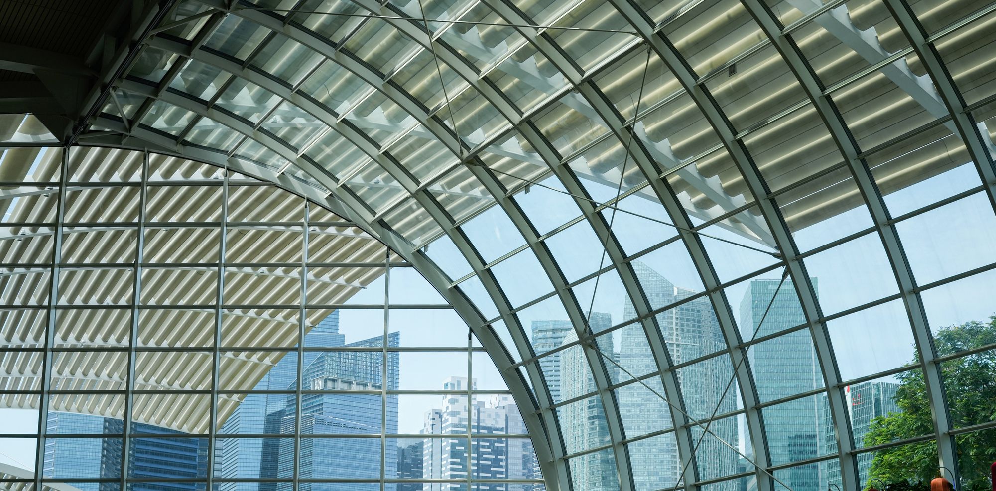 A glass-vaulted atrium opening onto a city skyline