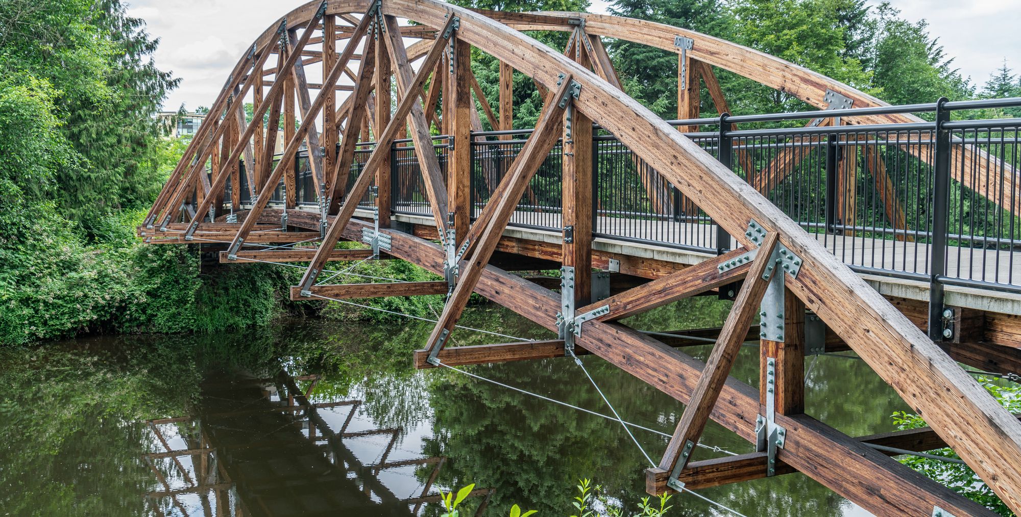 A timber footbridge spanning a river between two wooded banks