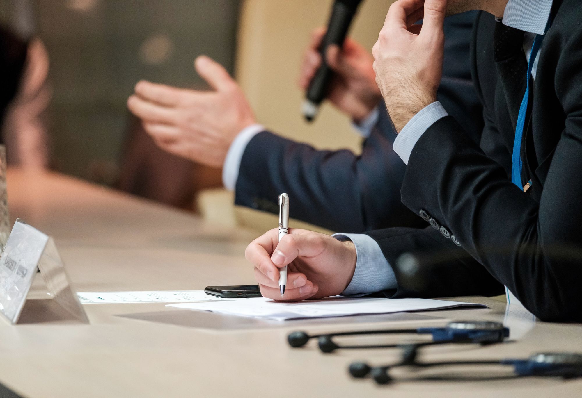 Leaders seated around a conference table, one taking notes