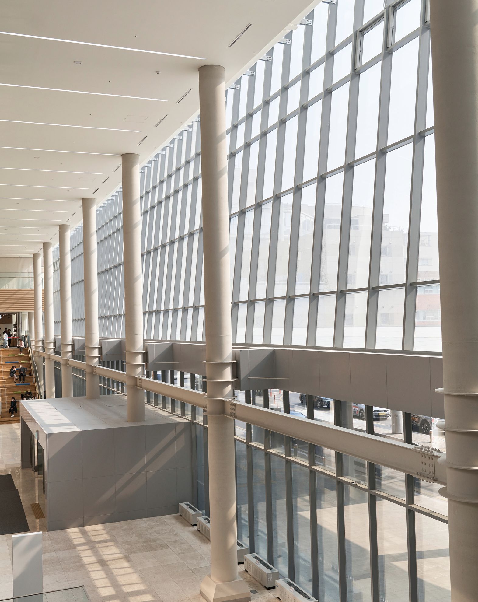 A light-filled building corridor lined with tall windows